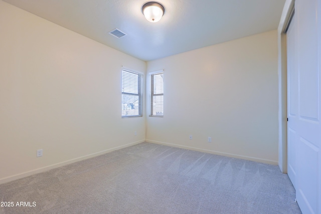 empty room featuring baseboards, visible vents, and light carpet