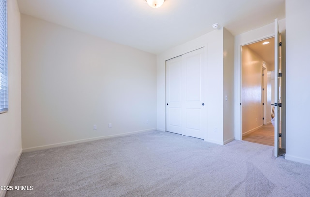 unfurnished bedroom featuring carpet floors, baseboards, and a closet