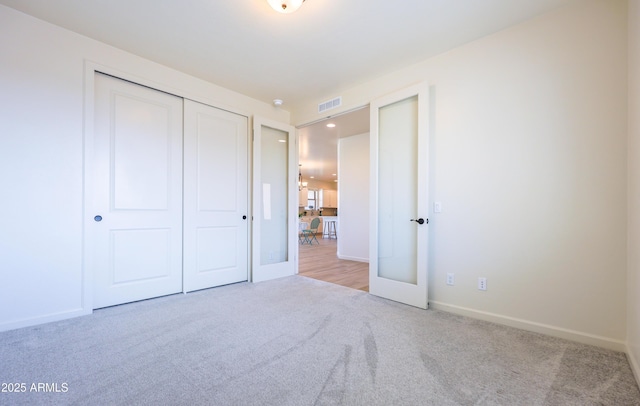 unfurnished bedroom featuring visible vents, carpet flooring, baseboards, and a closet