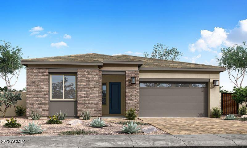 prairie-style home featuring a garage, brick siding, decorative driveway, and stucco siding