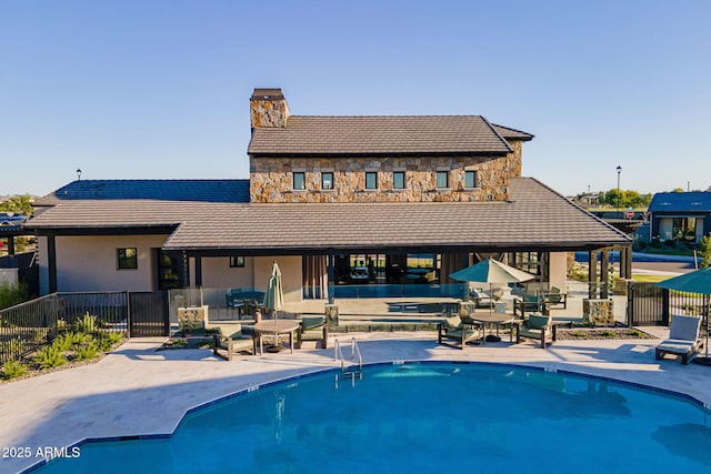 rear view of property with a community pool and a patio