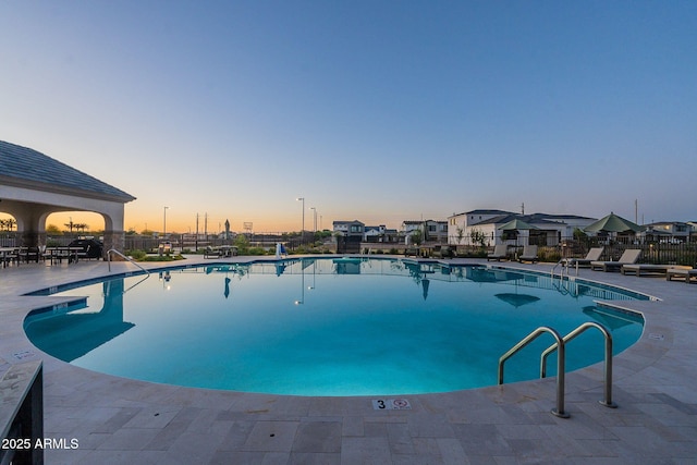 pool at dusk featuring a patio area