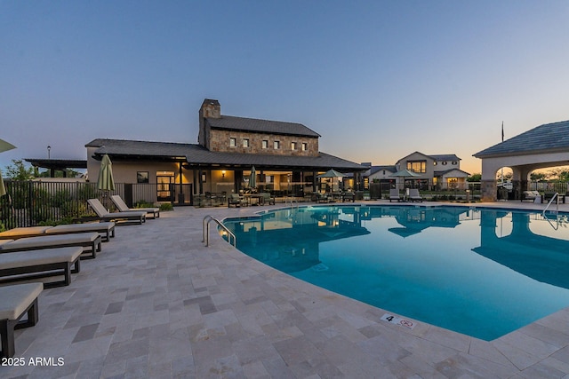 pool at dusk with a patio area