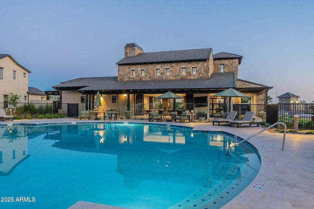 pool at dusk with a patio area