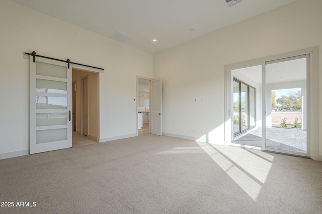 carpeted empty room featuring a barn door