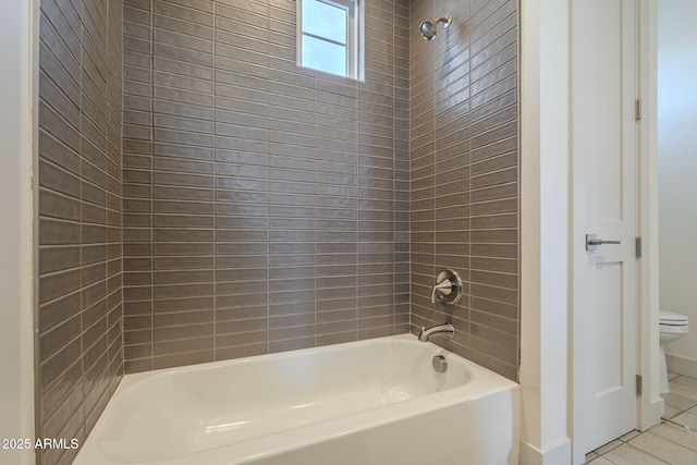 bathroom with tile patterned flooring, tiled shower / bath combo, and toilet