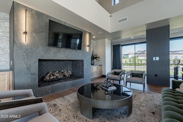 living room with wood-type flooring, a wealth of natural light, and a high end fireplace