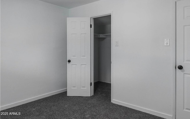 unfurnished bedroom with a closet and dark colored carpet