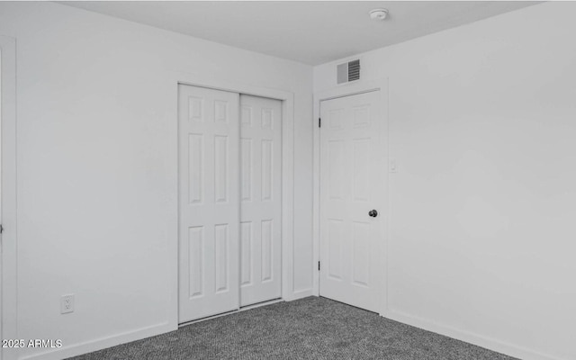 unfurnished bedroom featuring a closet and dark carpet