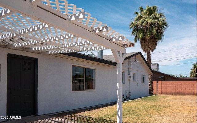 view of side of property featuring a pergola and a lawn