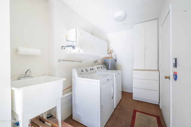 washroom featuring electric water heater, a textured ceiling, washing machine and dryer, cabinets, and sink