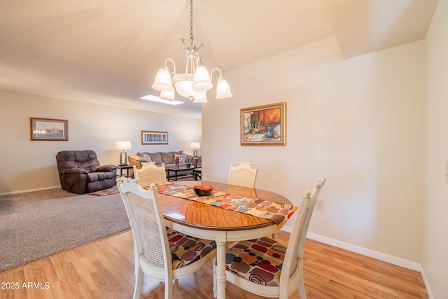 dining area with a notable chandelier, a textured ceiling, and light hardwood / wood-style flooring