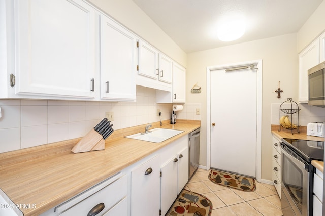 kitchen with sink, light tile patterned flooring, white cabinetry, and stainless steel appliances