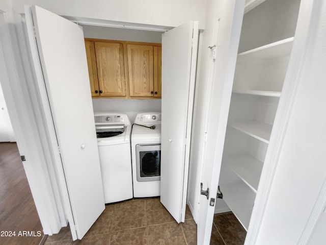 laundry area featuring cabinets, dark tile patterned flooring, and washer and dryer