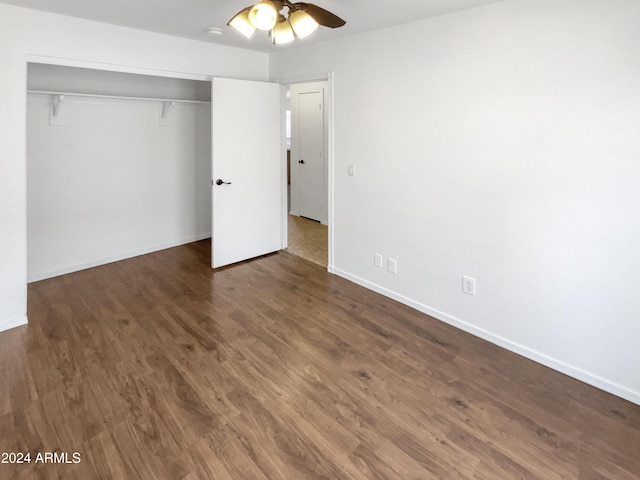 unfurnished bedroom with ceiling fan, dark wood-type flooring, and a closet