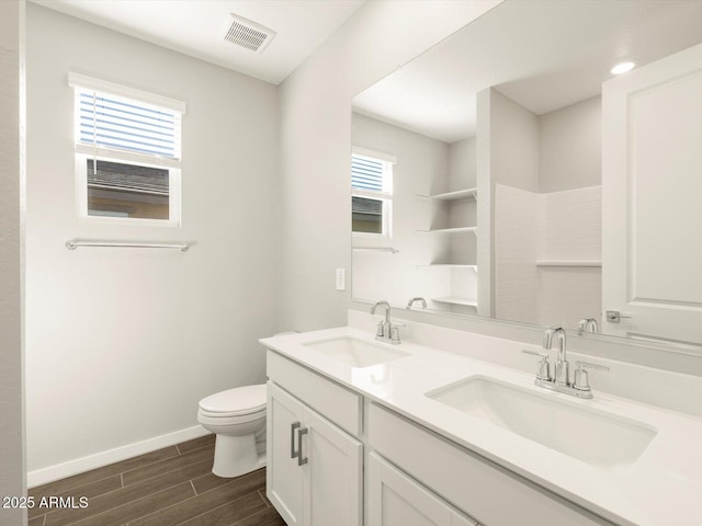 full bath with toilet, visible vents, a sink, and wood finish floors