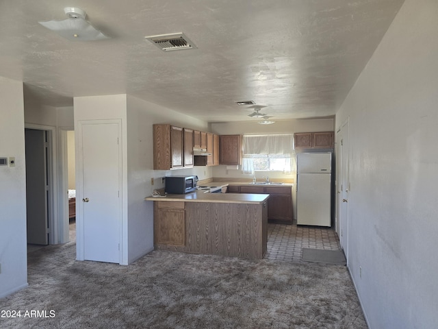 kitchen featuring white refrigerator, kitchen peninsula, a textured ceiling, and dark carpet