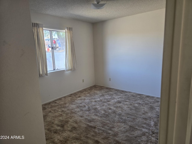 carpeted empty room with a textured ceiling