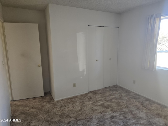 unfurnished bedroom with a textured ceiling, carpet floors, and a closet