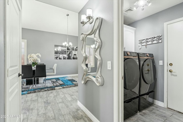 interior space featuring wood finish floors, cabinet space, visible vents, a chandelier, and washer and dryer