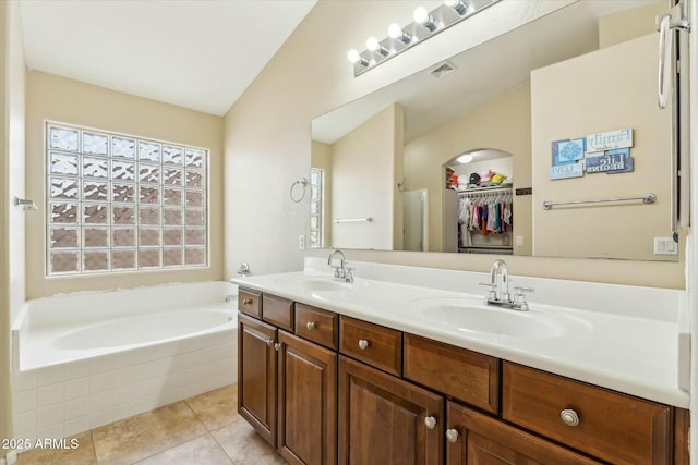 full bathroom with double vanity, a sink, a bath, and tile patterned floors