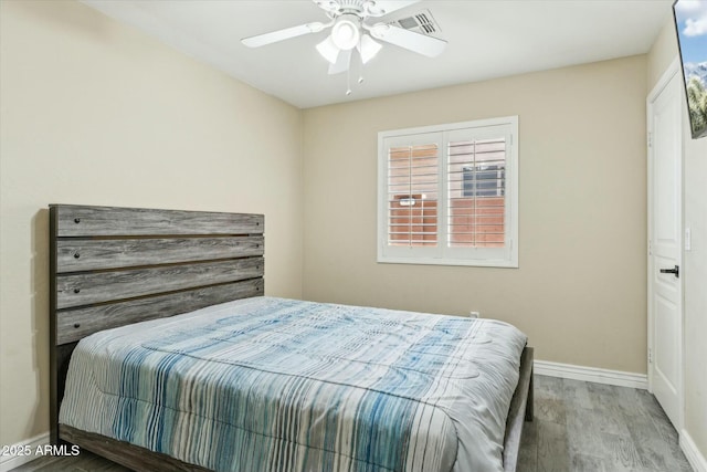 bedroom featuring baseboards, visible vents, ceiling fan, and wood finished floors