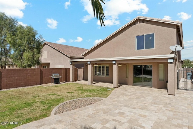 back of house featuring a patio, a lawn, fence, and stucco siding