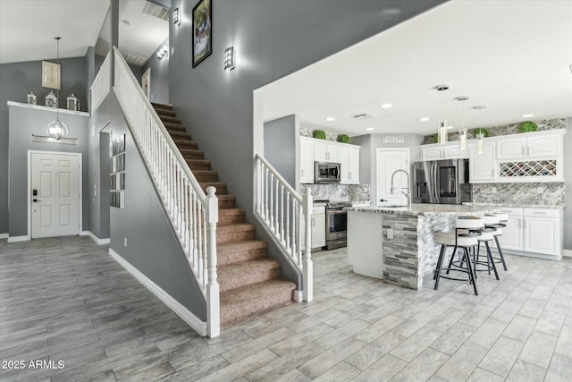 staircase featuring high vaulted ceiling, wood finished floors, visible vents, and baseboards