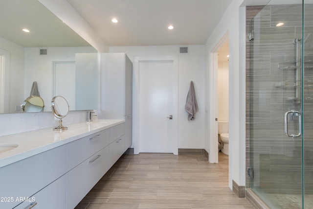 bathroom with vanity, an enclosed shower, and toilet