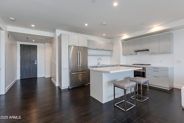 kitchen featuring sink, appliances with stainless steel finishes, a kitchen island, a kitchen bar, and dark hardwood / wood-style flooring