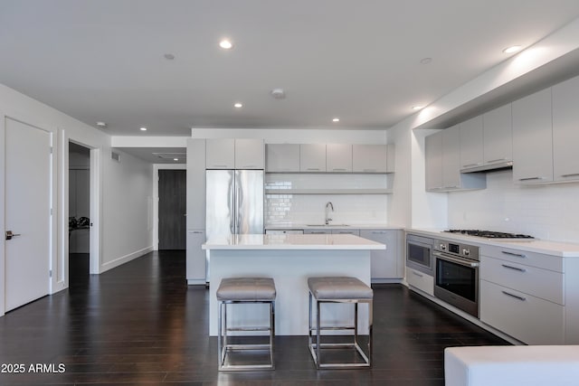 kitchen featuring dark wood-type flooring, sink, a breakfast bar area, a kitchen island, and stainless steel appliances