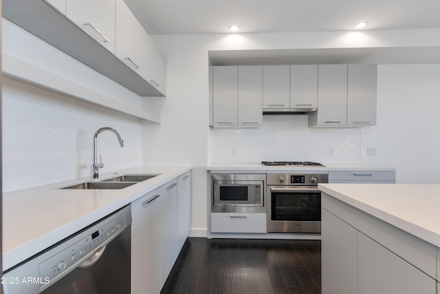 kitchen featuring sink, dark wood-type flooring, appliances with stainless steel finishes, tasteful backsplash, and white cabinets