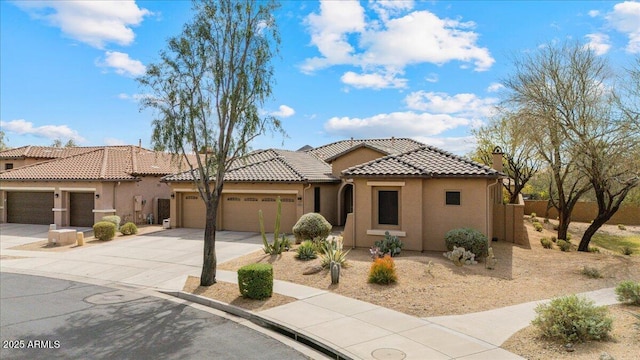 mediterranean / spanish house with a garage, concrete driveway, stucco siding, and a tiled roof