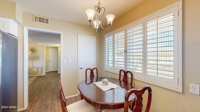 dining space featuring dark hardwood / wood-style flooring and an inviting chandelier