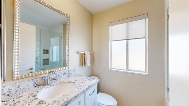 bathroom featuring a shower with shower door, vanity, and toilet