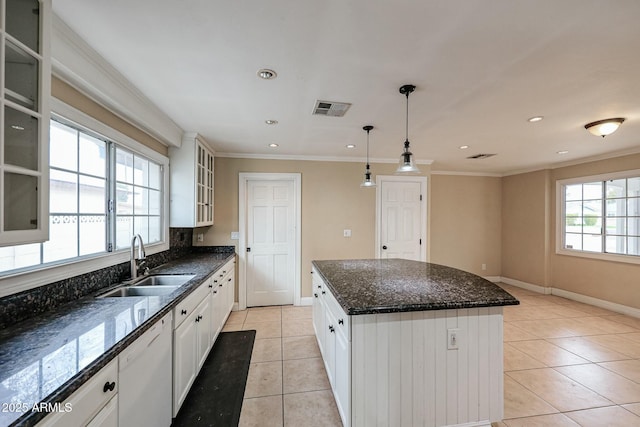 kitchen featuring a sink, visible vents, white cabinetry, a center island, and glass insert cabinets