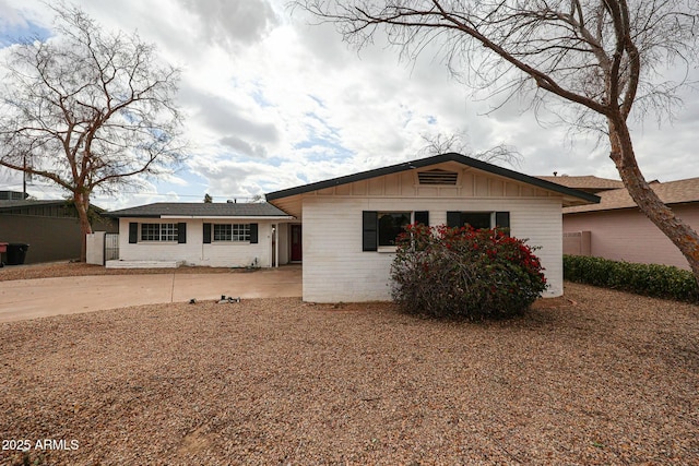 view of front of property with a patio, board and batten siding, and brick siding