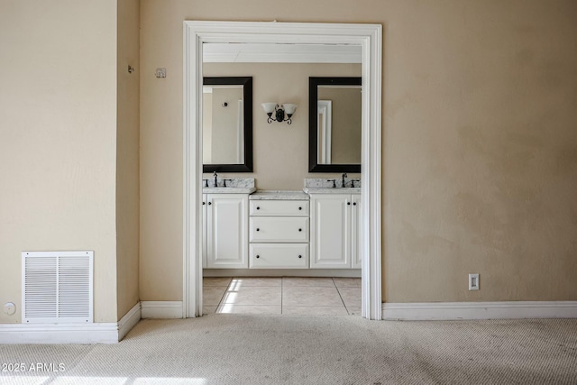 full bath with double vanity, baseboards, visible vents, and a sink