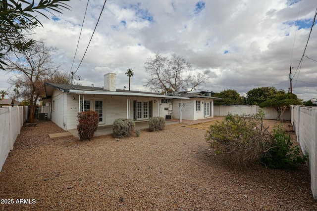 back of property with a fenced backyard, a patio, and a chimney