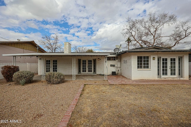 rear view of house with a chimney, fence, french doors, a patio area, and central AC