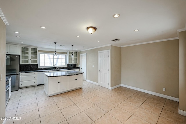 kitchen featuring glass insert cabinets, a center island, hanging light fixtures, white cabinetry, and a sink