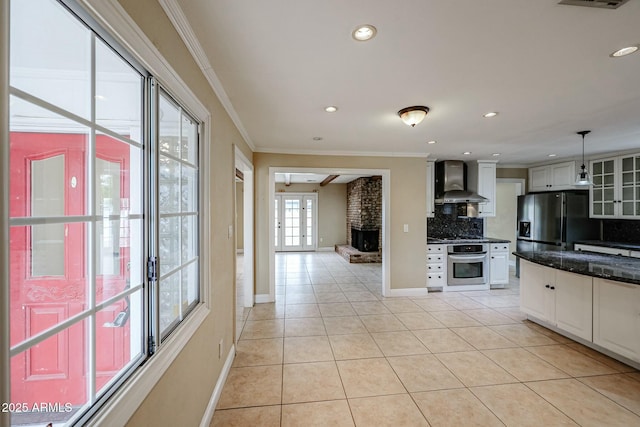 kitchen with pendant lighting, light tile patterned floors, appliances with stainless steel finishes, white cabinets, and wall chimney exhaust hood