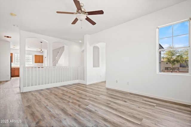 unfurnished room with light wood finished floors, a wealth of natural light, and a ceiling fan