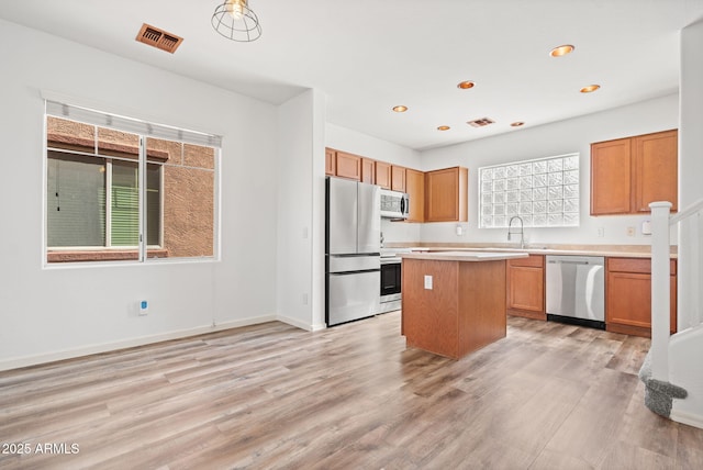 kitchen with visible vents, a center island, appliances with stainless steel finishes, light wood finished floors, and light countertops