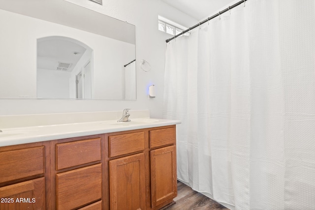 full bath with a sink, visible vents, wood finished floors, and double vanity