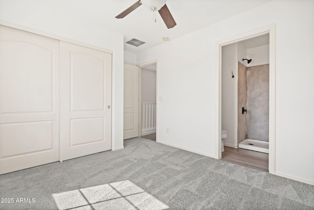 unfurnished bedroom featuring visible vents, carpet floors, ceiling fan, a closet, and ensuite bathroom