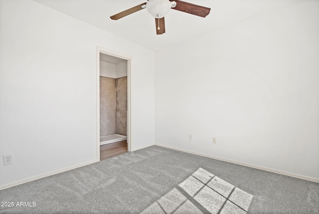 carpeted spare room featuring baseboards and a ceiling fan