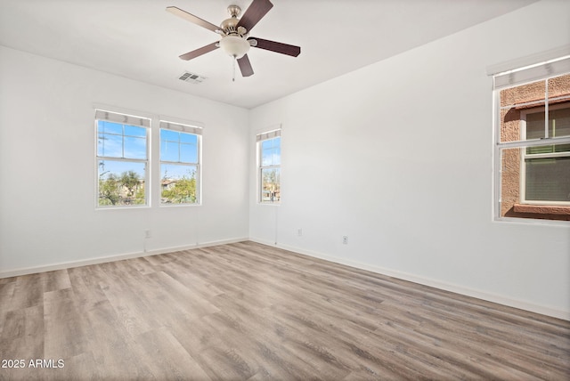 empty room with ceiling fan, visible vents, baseboards, and wood finished floors