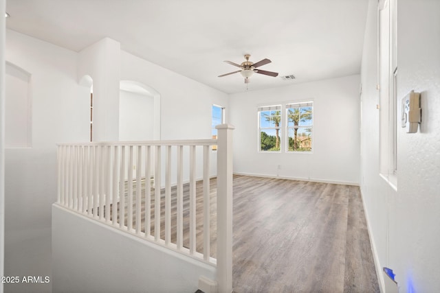 hall with an upstairs landing, visible vents, baseboards, and wood finished floors