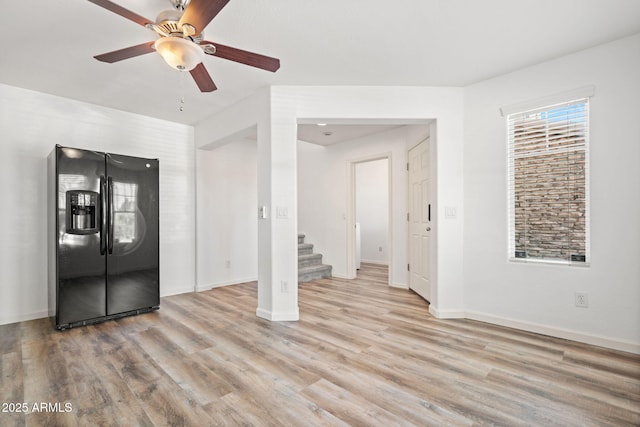 unfurnished living room with stairs, baseboards, light wood-type flooring, and ceiling fan